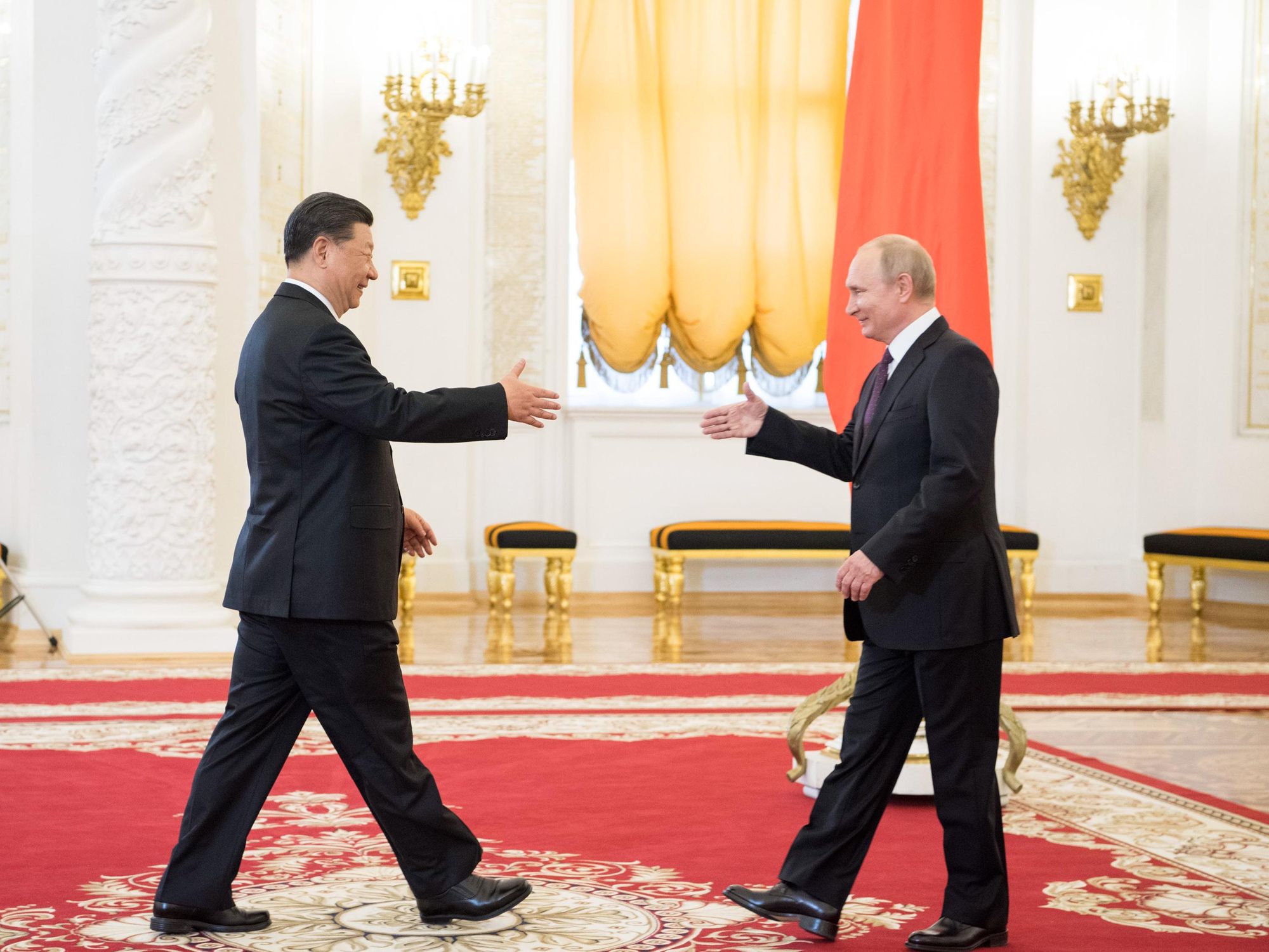 Xi Jinping and Vladimir Putin walking towards each other to shake hands