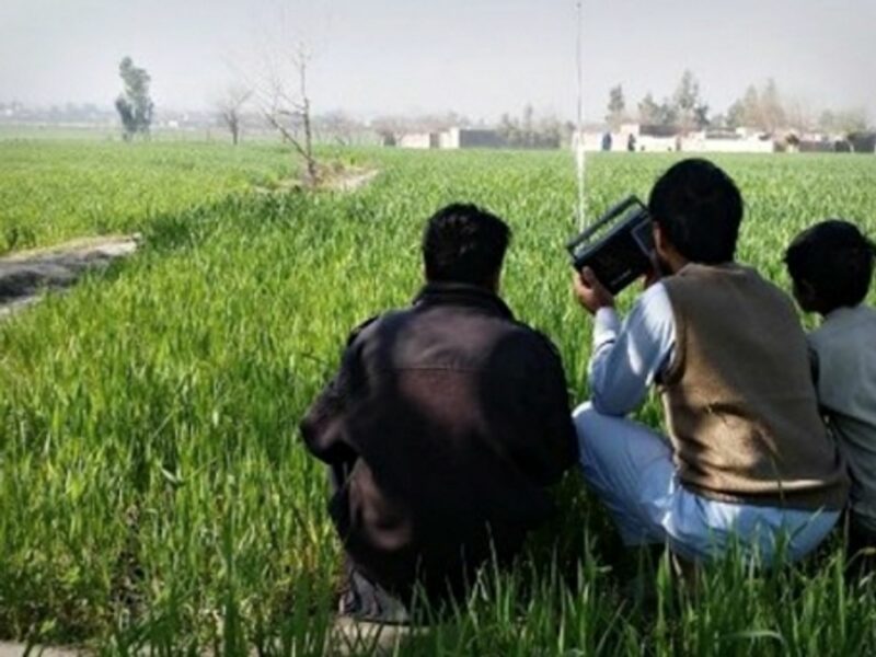 Young Afghans listening to the radio in a field