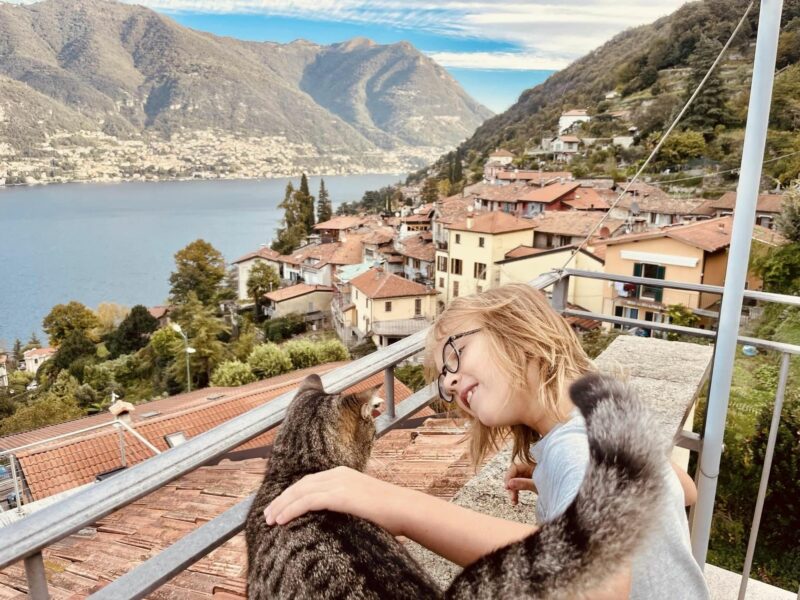 Young girl and a cat on a terrace facing Lake Como.