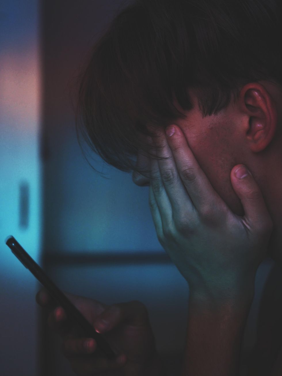Young man holding a smartphone in a dark room