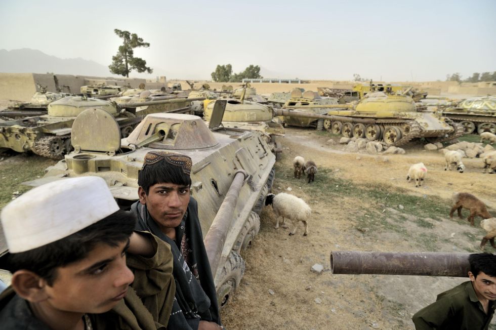 Young men are sitting on Russian tanks in Afghanistan, abandoned during the Soviet-Afghan war