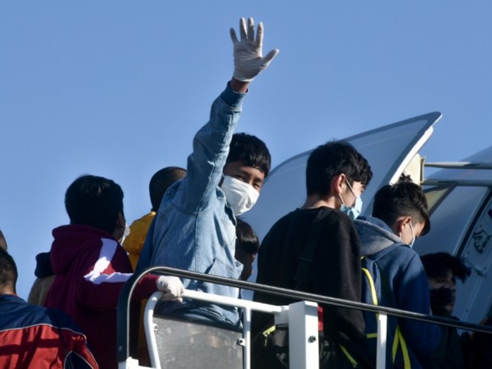 Young migrants board an airplane in Athens.