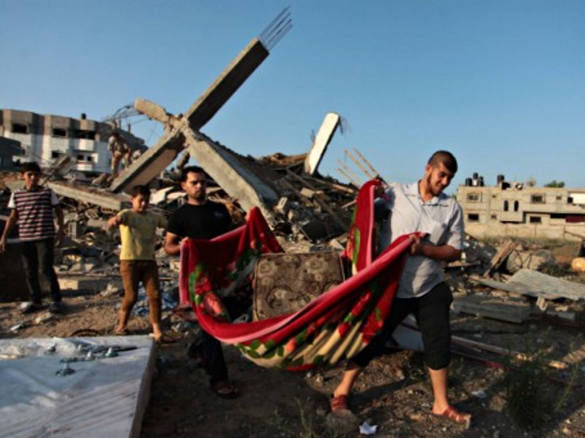Young Palestinians carry their belongings as they walk past the rubble of their family's house destroyed by an Israeli air strike in Gaza.