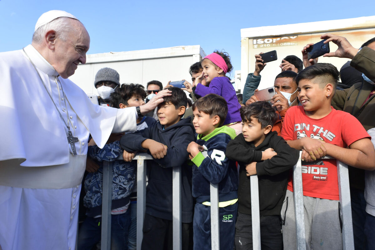 Pope Francis puts his hand on the head of a boy in a crowd as he goes by