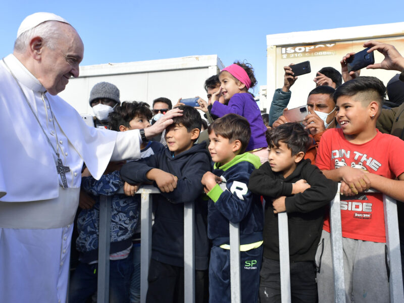 Pope Francis puts his hand on the head of a boy in a crowd as he goes by
