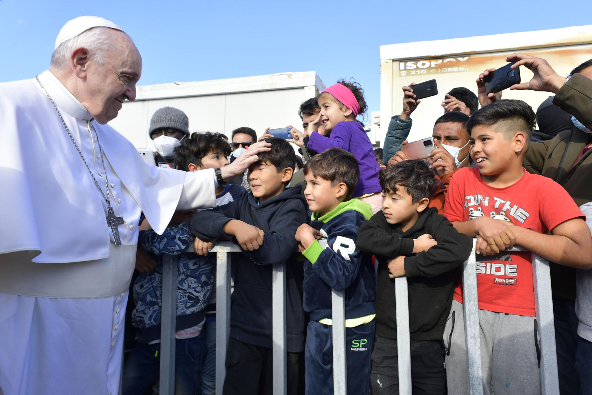 Pope Francis puts his hand on the head of a boy in a crowd as he goes by