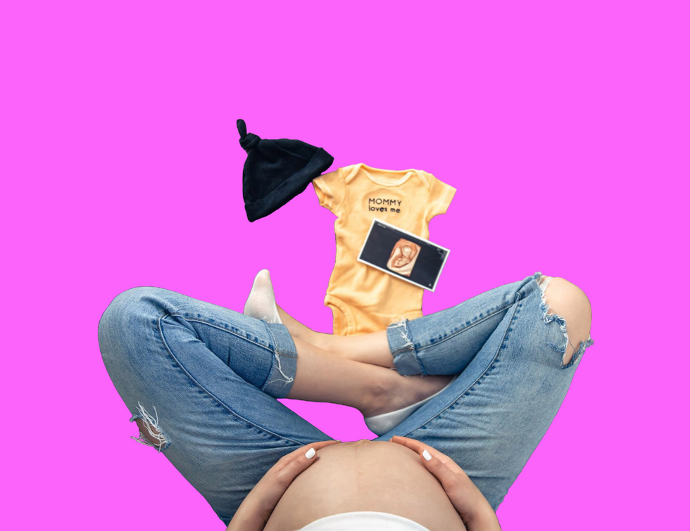 A pregnant woman, seen from the top down, is cross legged and sits near baby clothes