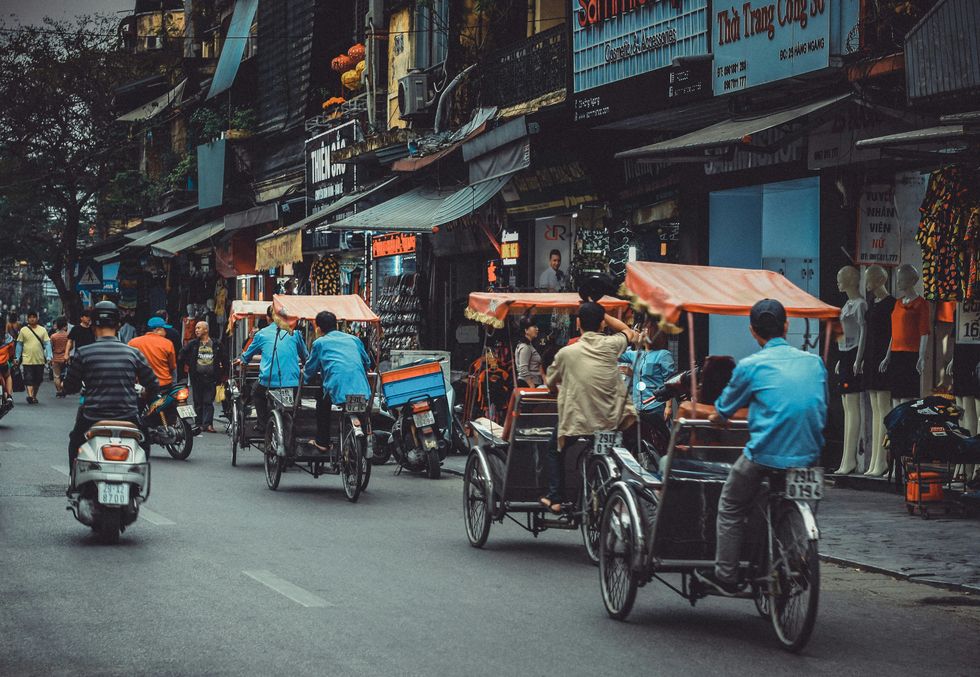 Man driving white motor scooter on road.
