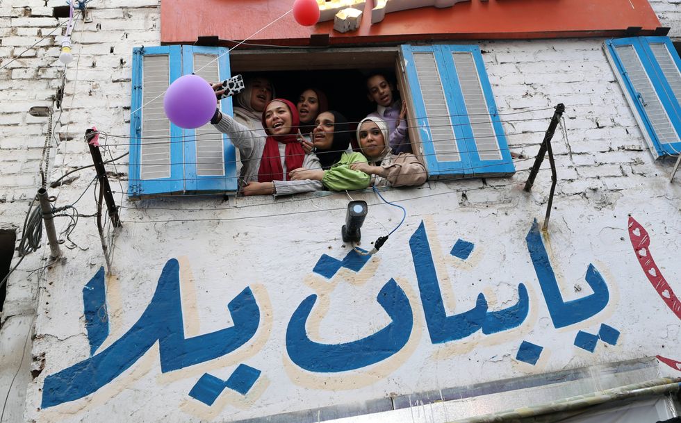 Photo of Egyptian women and girls taking selfies from a Cairo window
