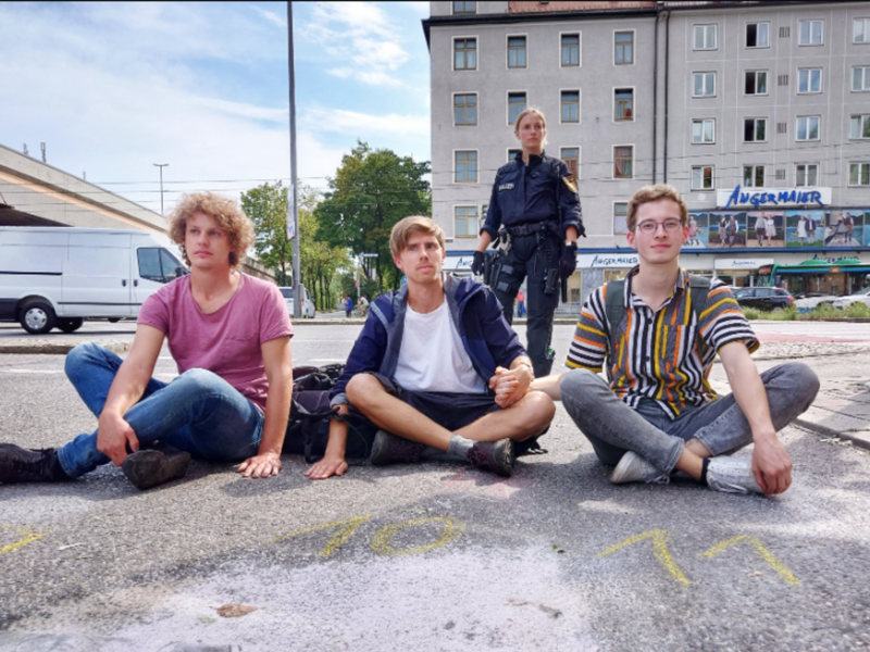 photo of three young men sitting on the road
