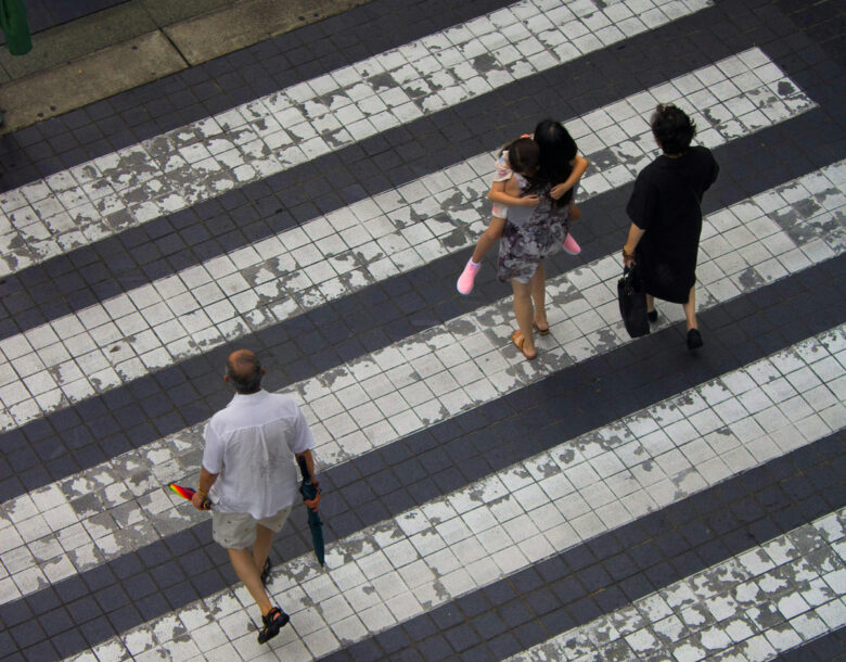 Photo of people walking across a sidewalk.