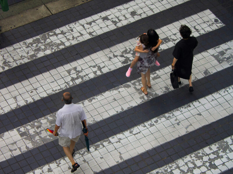Photo of people walking across a sidewalk.