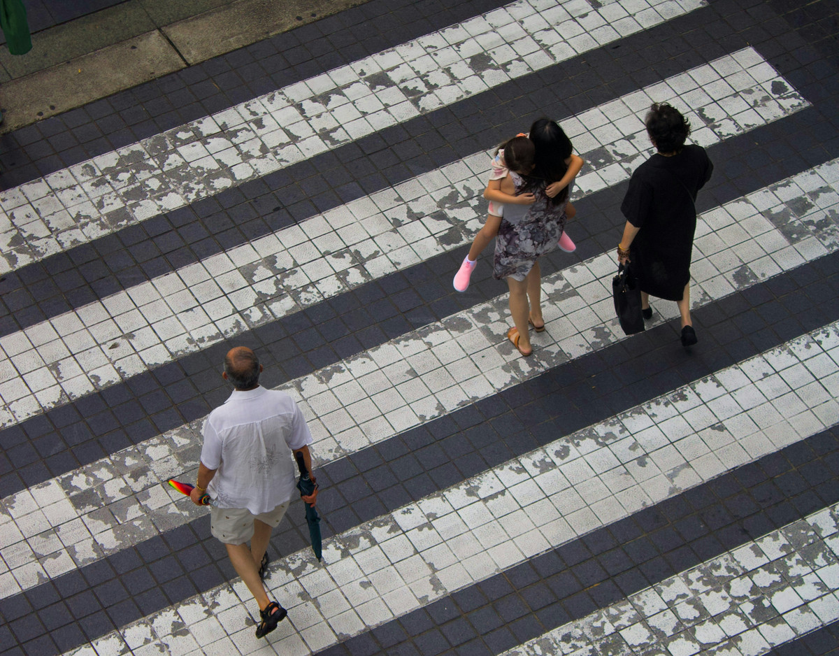 Photo of people walking across a sidewalk.