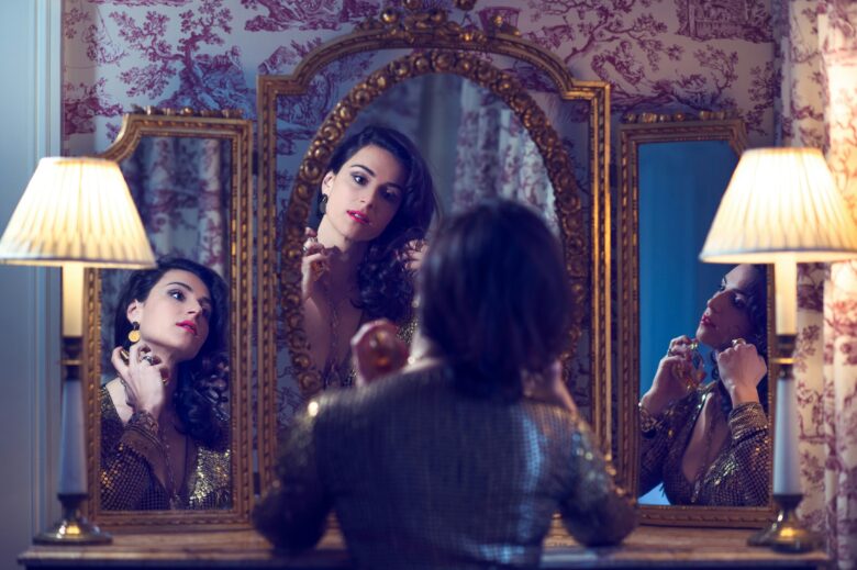 Photo of a woman applying make up in front of a mirror.
