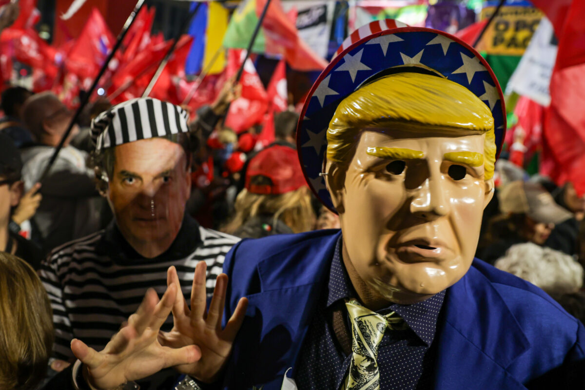 Photo of a caricatured costume of Trump and a mask with the image of former Brazilian President Bolsonaro in prisoner's clothing