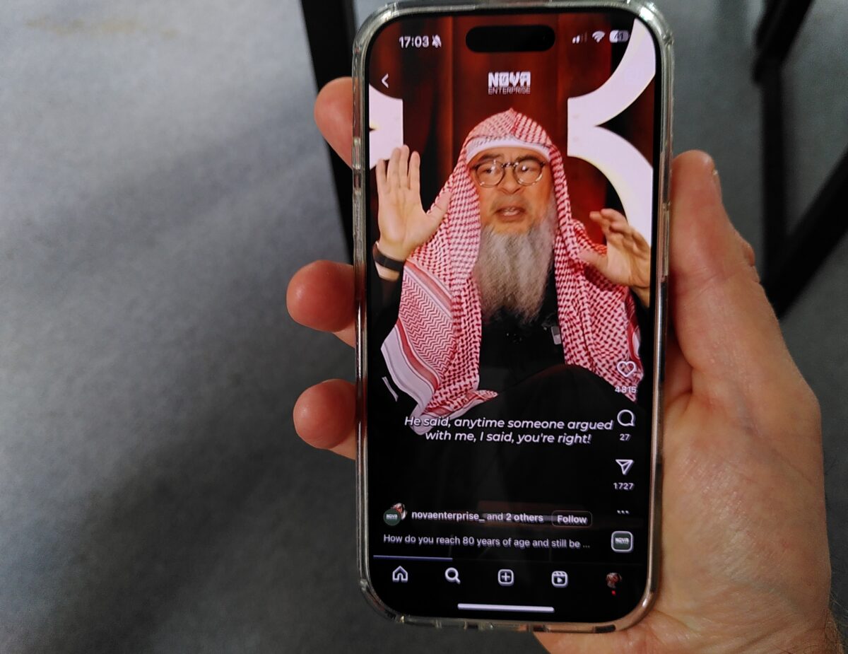 A phone displaying an Instagram video of Sheikh Assim Al-Hakeem.