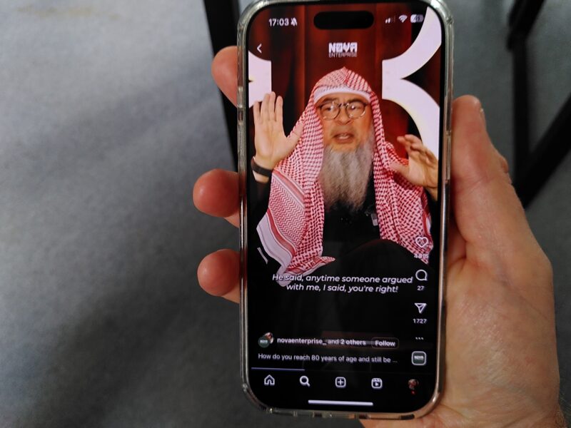 A phone displaying an Instagram video of Sheikh Assim Al-Hakeem.
