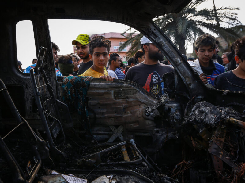 People inspecting a vehicle destroyed by an explosive device at a street market in the City of Sadr in eastern Baghdad, which killed at least one civilian and injured 12 on April 15, 2021, in Baghdad, Iraq.