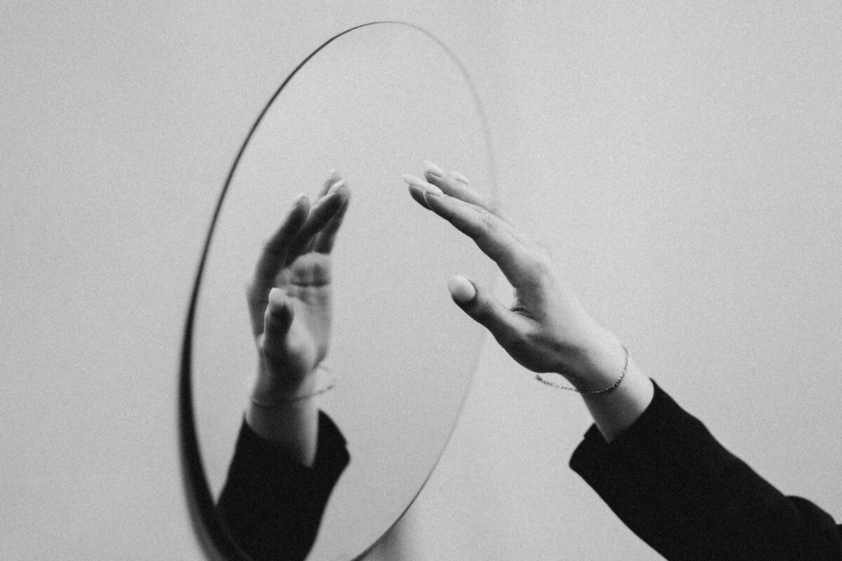 Person holds a hand up to a mirror.