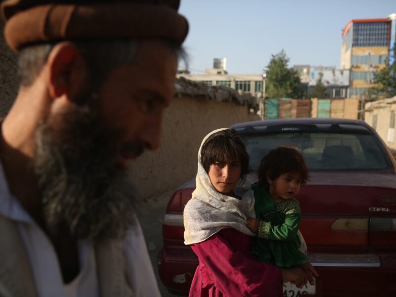 Photo of an an Afghan displaced child holding her baby sister in Kabul, Afghanistan in 2017.