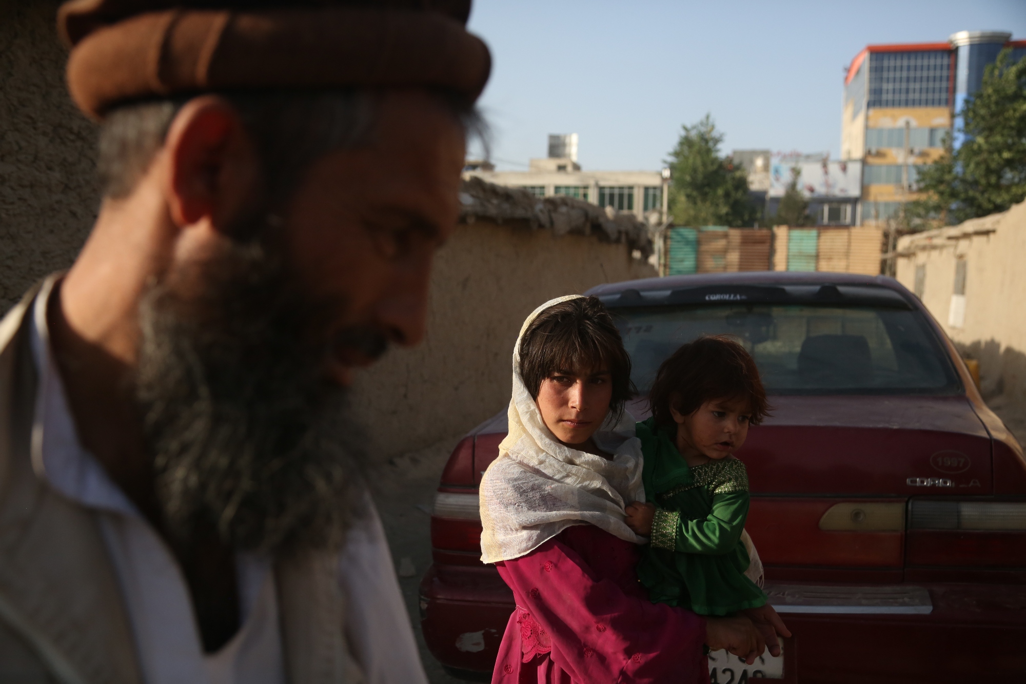 Photo of an an Afghan displaced child holding her baby sister in Kabul, Afghanistan in 2017.