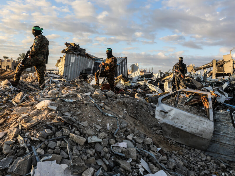 Fighters of the Ezz al-Din Al-Qassam brigades, the military wing of Hamas stand guard around ruins as Israeli hostages get delivered to representatives of the International Committee of the Red Cross on Feb. 1 2025 in Gaza.