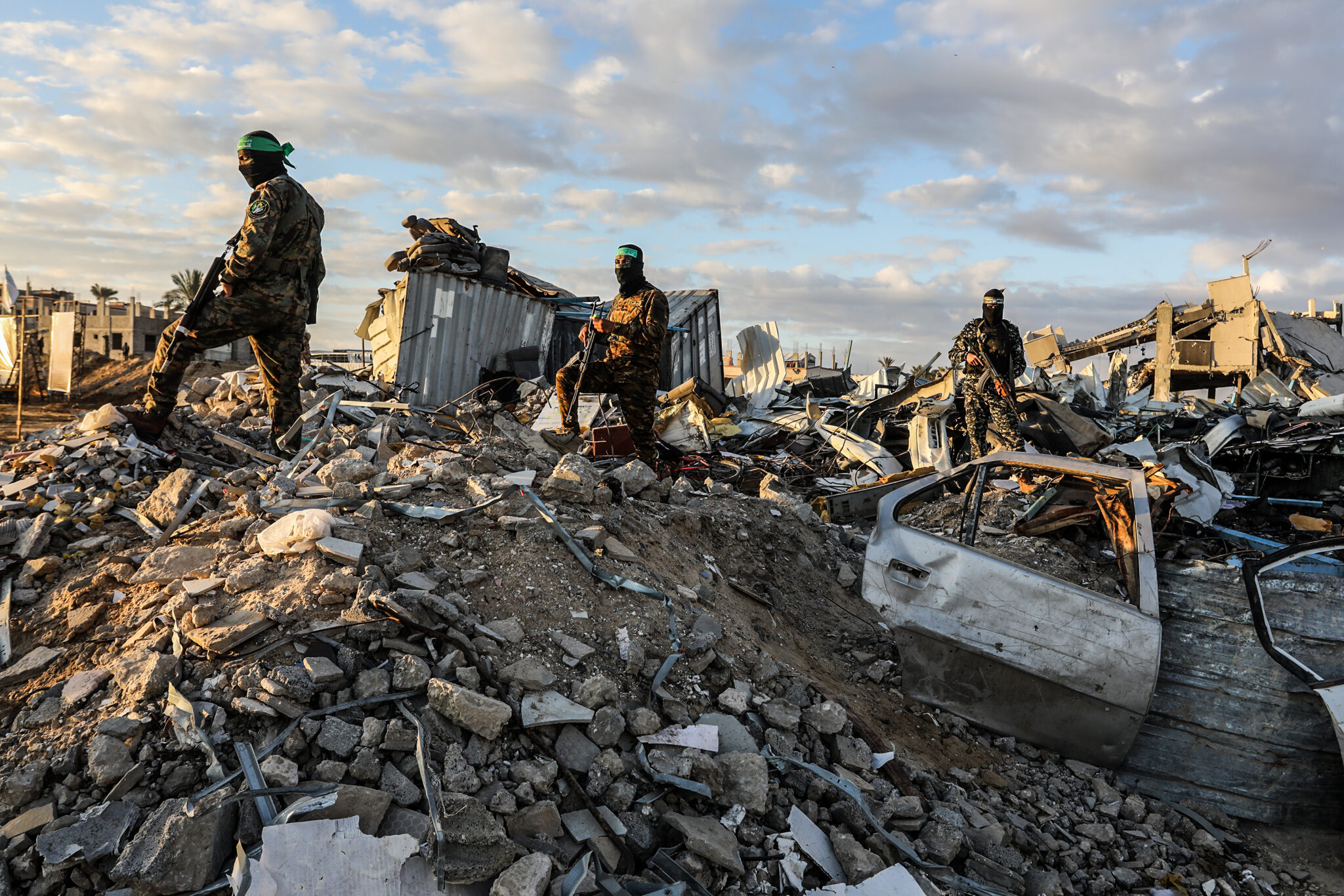 Fighters of the Ezz al-Din Al-Qassam brigades, the military wing of Hamas stand guard around ruins as Israeli hostages get delivered to representatives of the International Committee of the Red Cross on Feb. 1 2025 in Gaza.