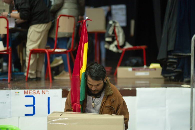 Photo of a voter holding the Bolivian flag filling out his ballot during the 2025 presidential election.