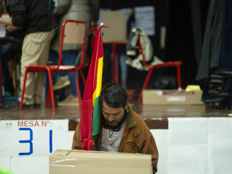 Photo of a voter holding the Bolivian flag filling out his ballot during the 2025 presidential election.