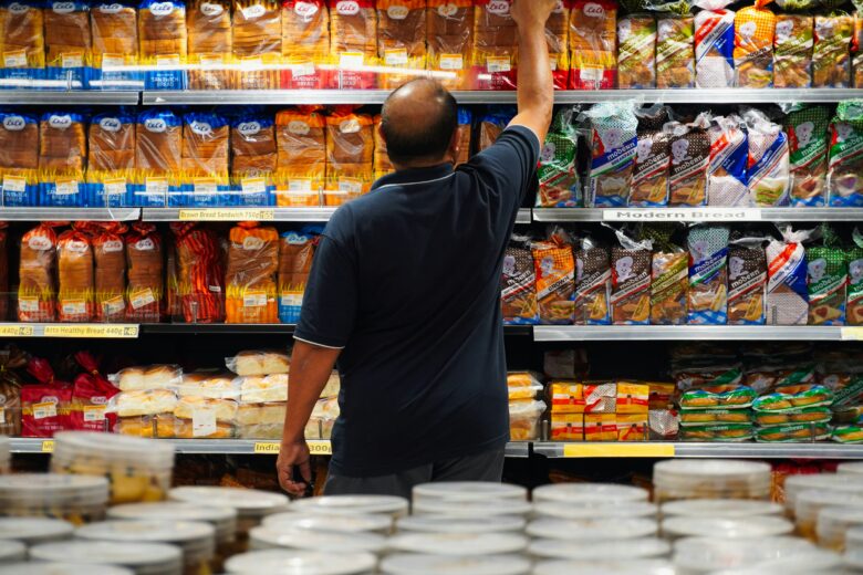 Man reaching for bread on a grocery store shelf