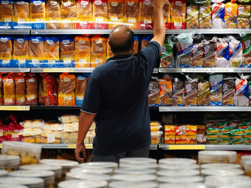 Man reaching for bread on a grocery store shelf
