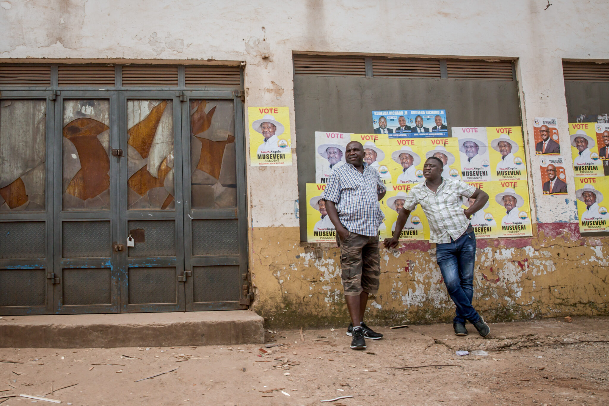 Kampala, Central Region, Uganda: Men stand in front of posters of Yoweri Museveni, Uganda's long-time president.