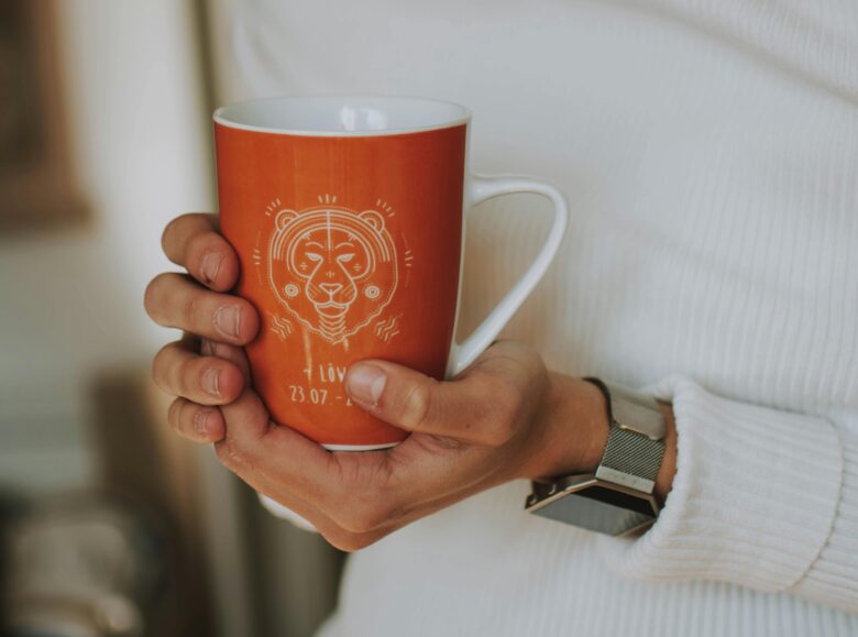 Person holding a cup decorated with an astrological sign graphic