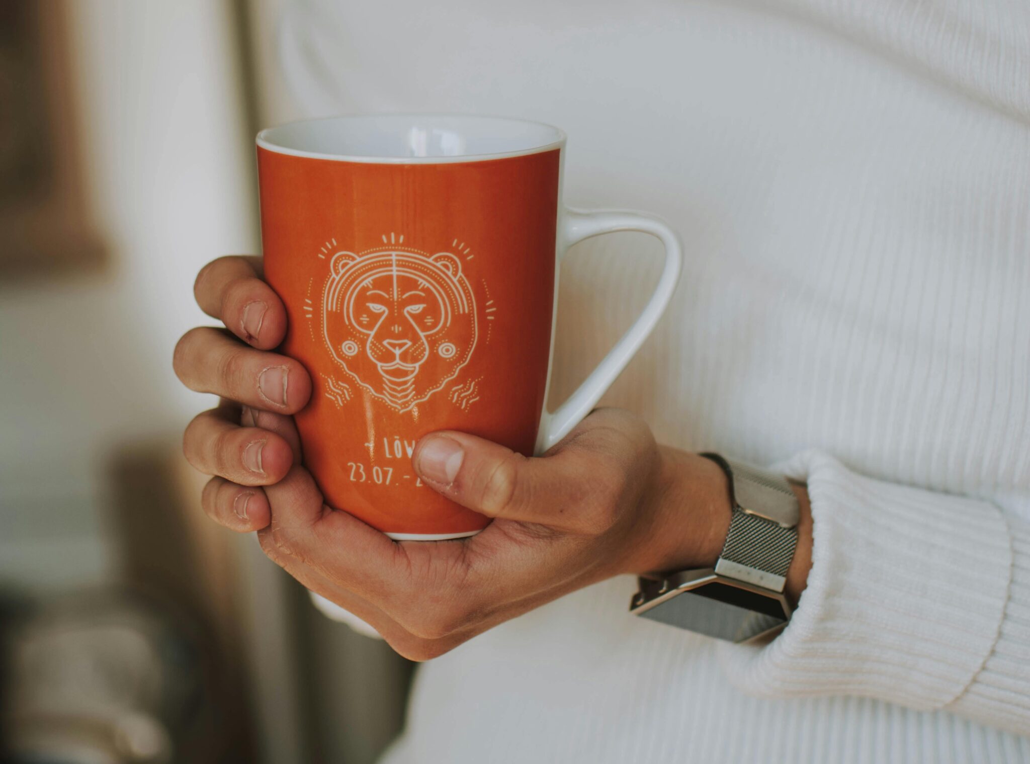 Person holding a cup decorated with an astrological sign graphic