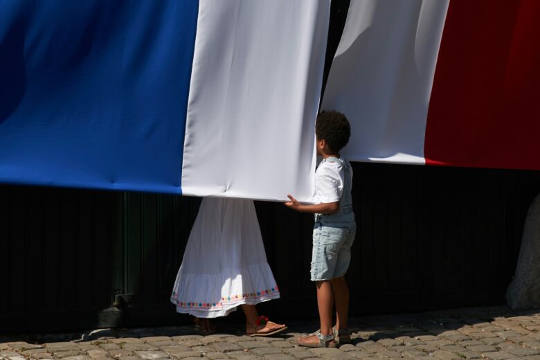 a child looking behind a French flag