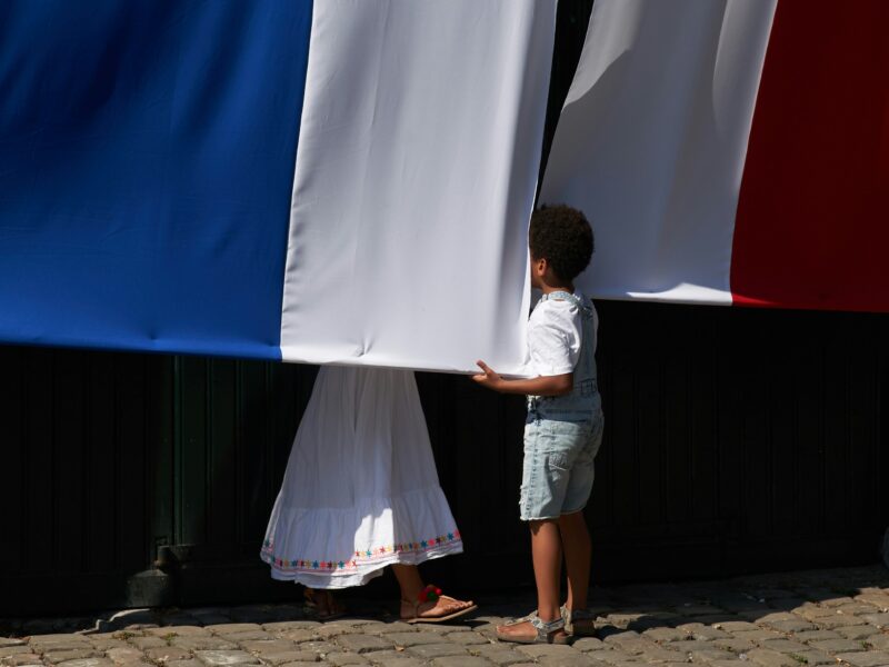 a child looking behind a French flag