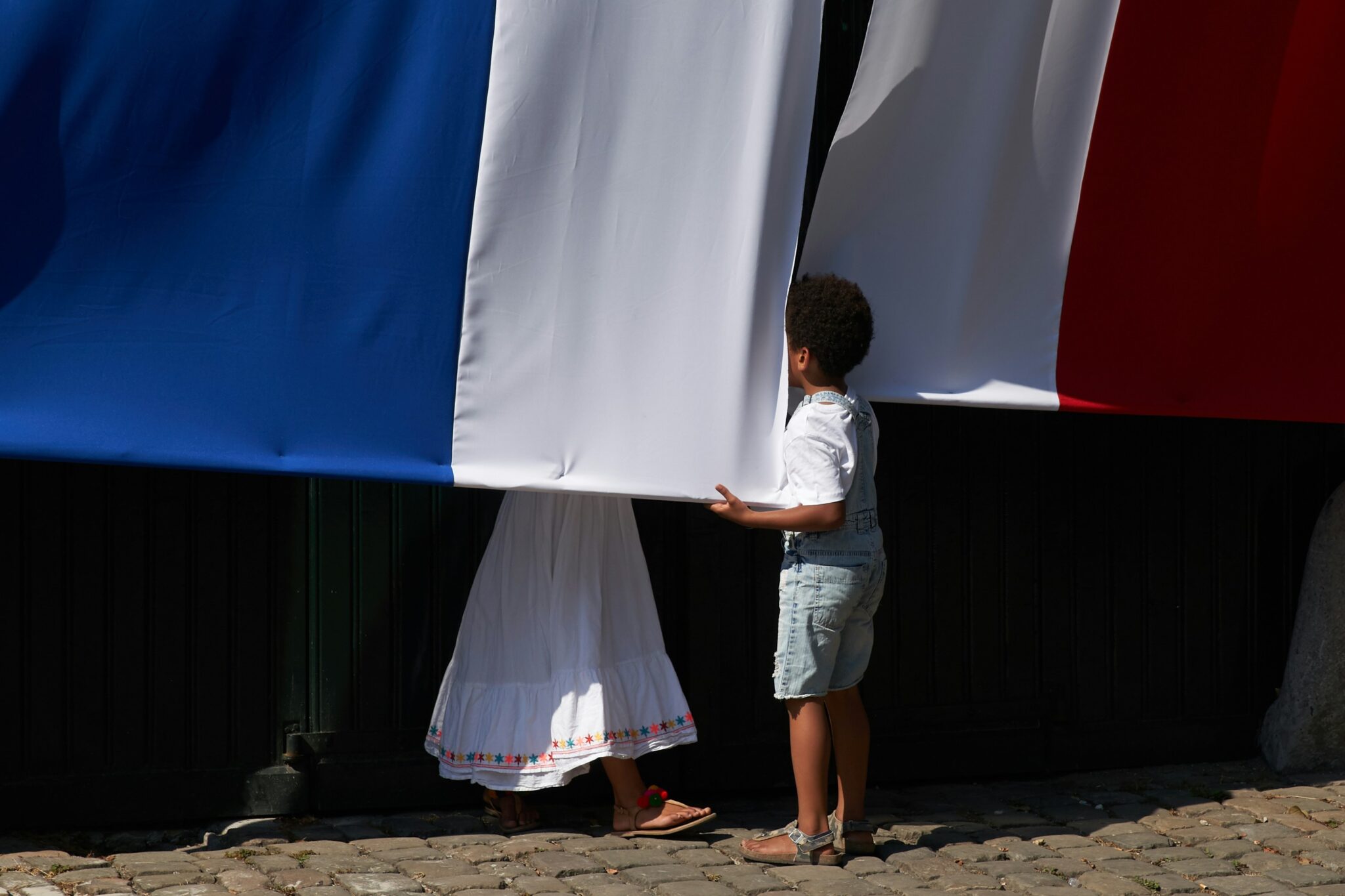 a child looking behind a French flag