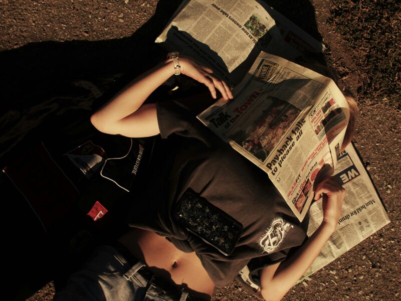 Woman covering her face with a newspaper