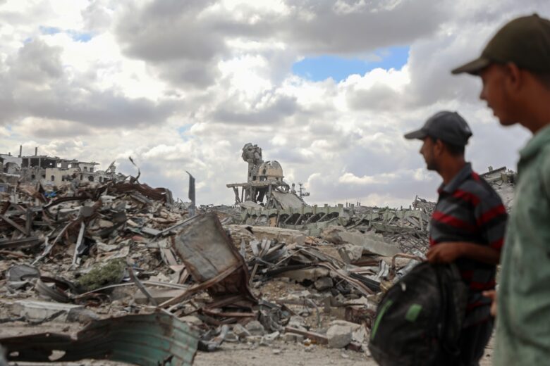 Palestinians walk past the rubble of destroyed buildings after returning to Khan Younis, in southern Gaza, on Oct. 12, 2025.