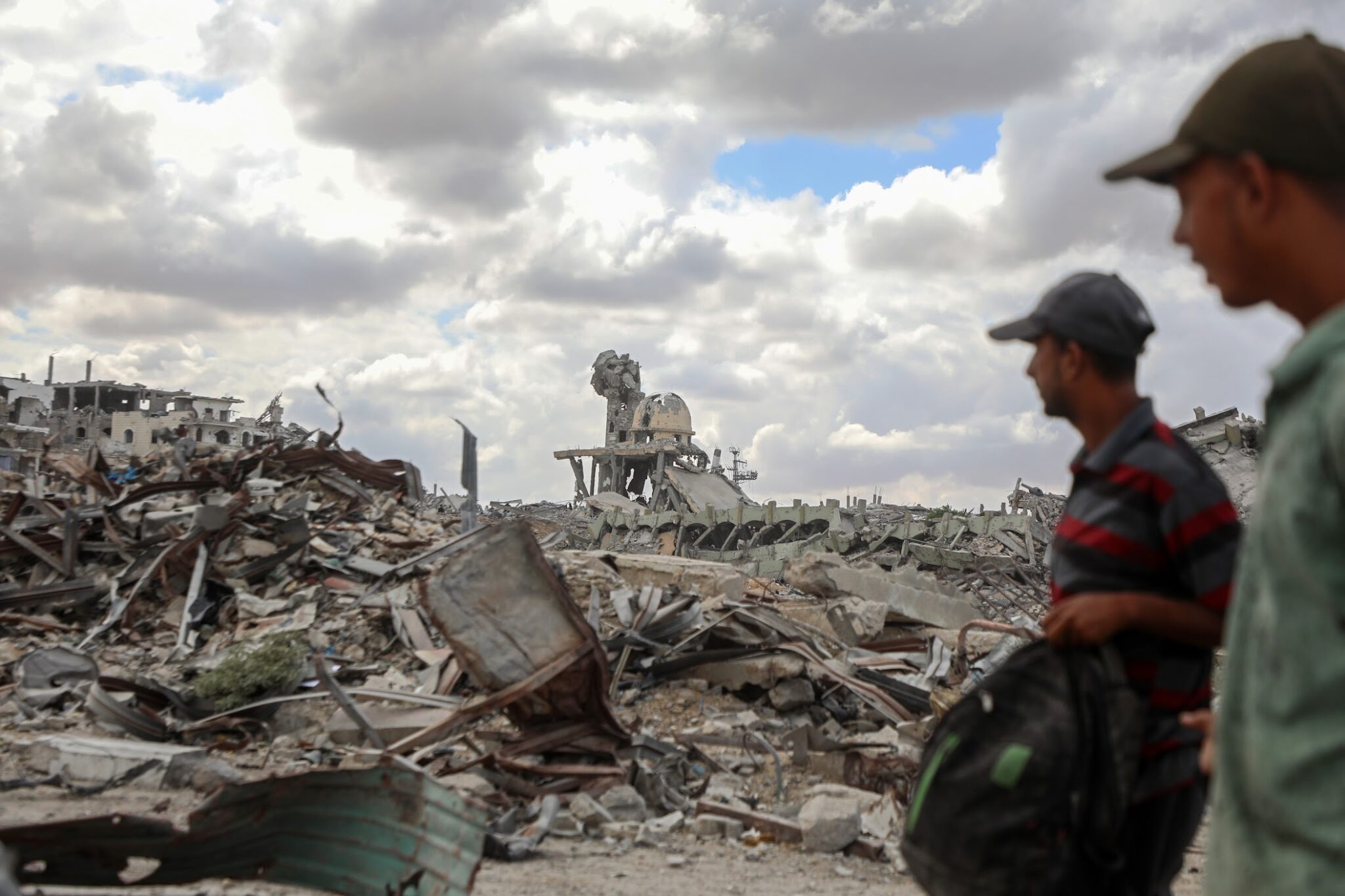 Palestinians walk past the rubble of destroyed buildings after returning to Khan Younis, in southern Gaza, on Oct. 12, 2025.
