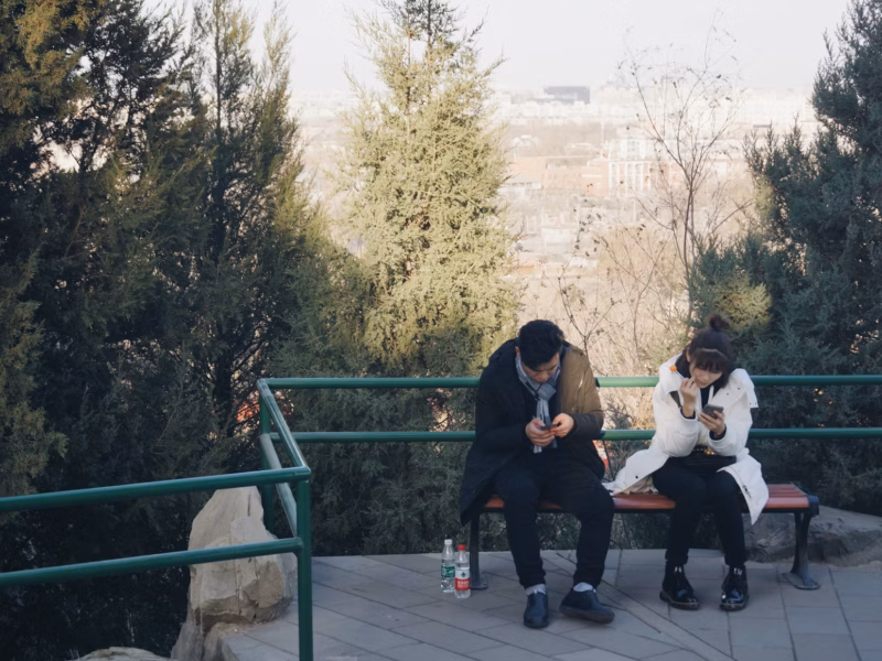 Couple sitting on a bench, phones in hand