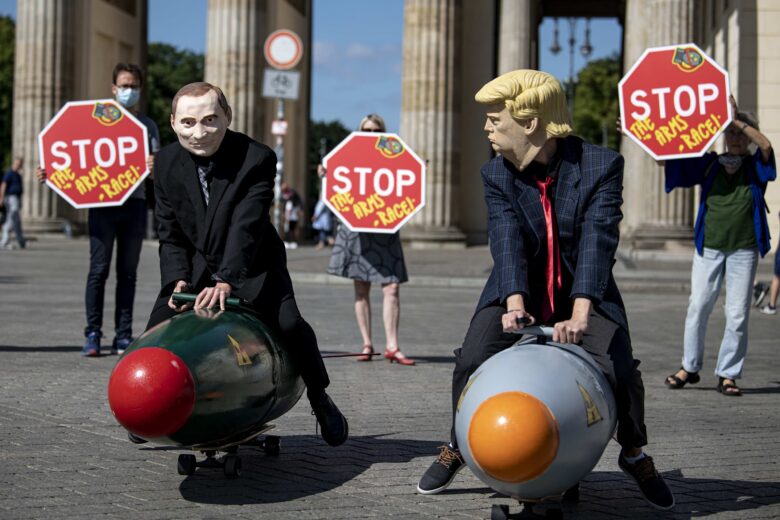 Two activists dressed as US President Trump and Russian President Putin ride two models of nuclear bombs in front of the Brandenburg Gate during a demonstration.