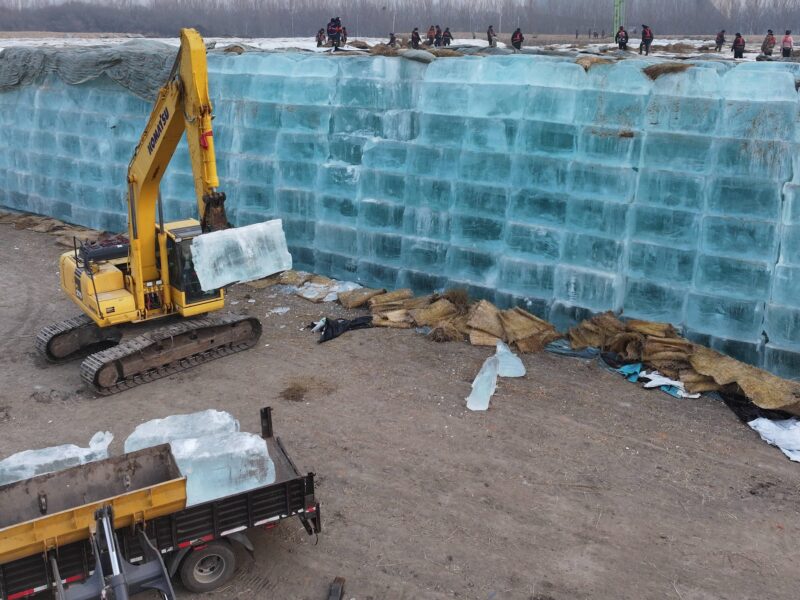 An excavator transfers stored ice to be used in the constructions of ice-built landscapes for the 27th Harbin Ice-Snow World on November 24, 2025 in Harbin, Heilongjiang Province of China.