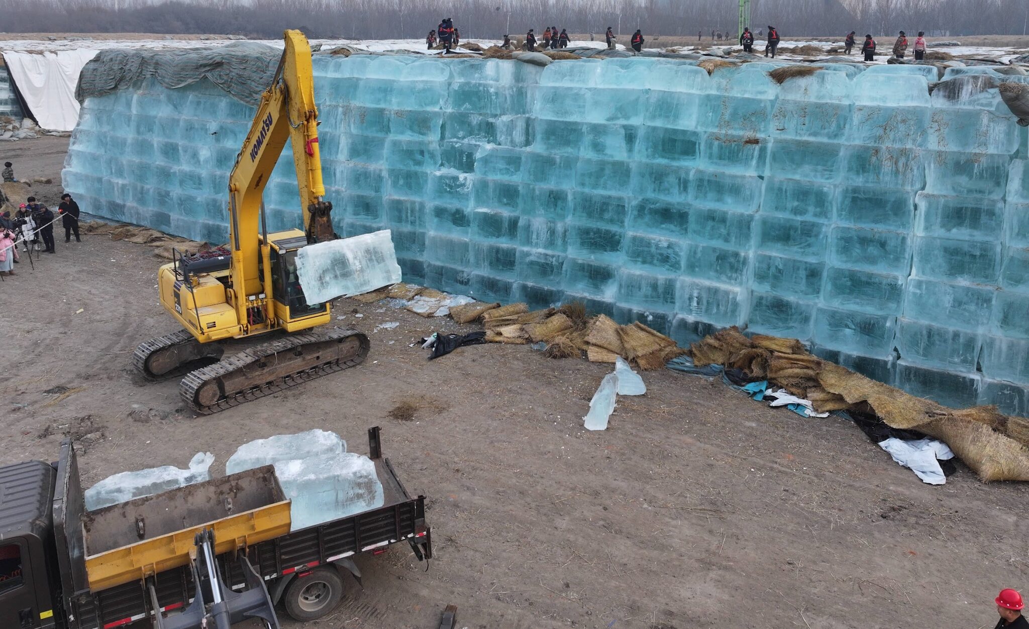 An excavator transfers stored ice to be used in the constructions of ice-built landscapes for the 27th Harbin Ice-Snow World on November 24, 2025 in Harbin, Heilongjiang Province of China.