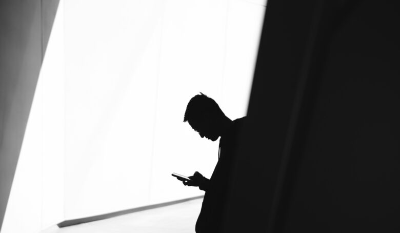 Silhouette of a person looking at their phone.