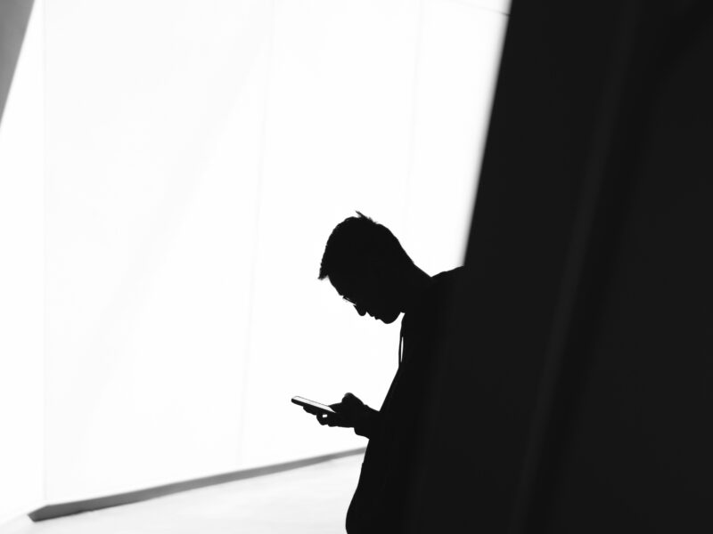 Silhouette of a person looking at their phone.