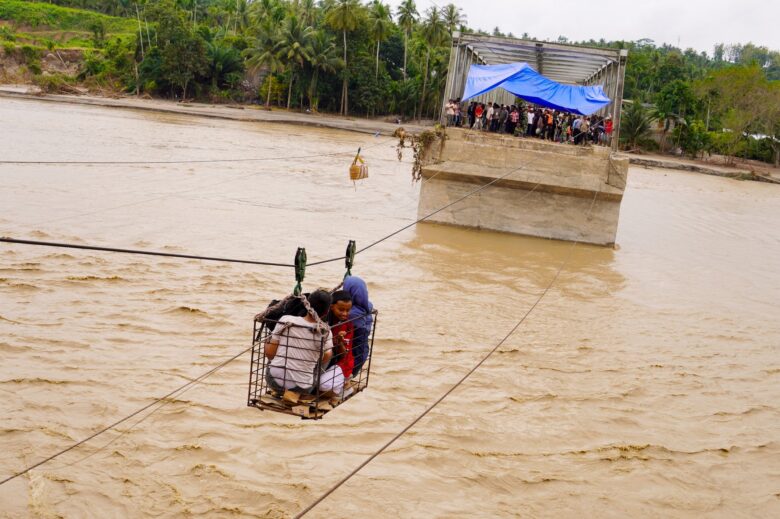 Residents use a steel cable to cross the Peusangan River after the Juli Bridge collapsed on the Bireuen-Takengon highway. December 2, 2025, Juli, Indonesia