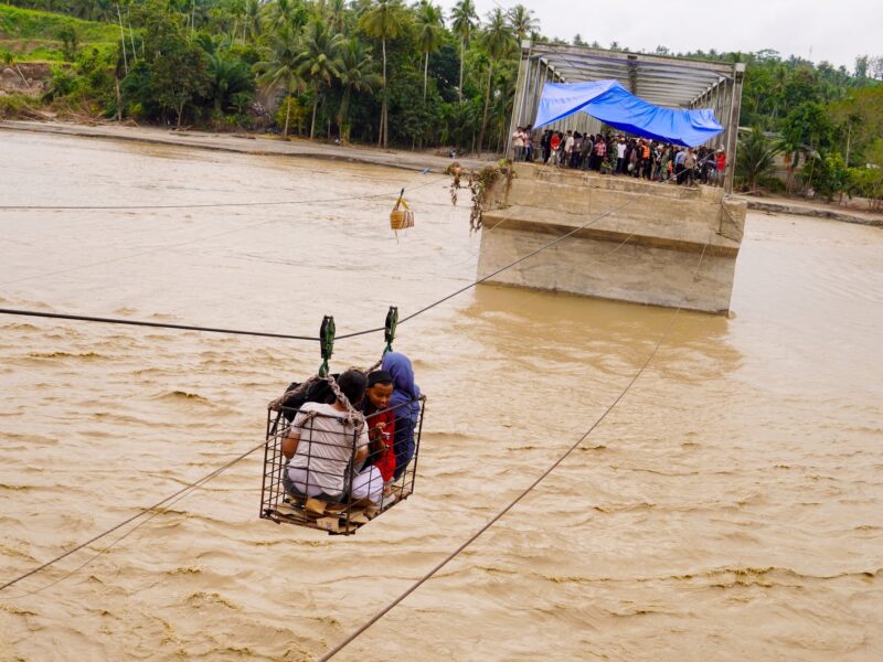 Residents use a steel cable to cross the Peusangan River after the Juli Bridge collapsed on the Bireuen-Takengon highway. December 2, 2025, Juli, Indonesia